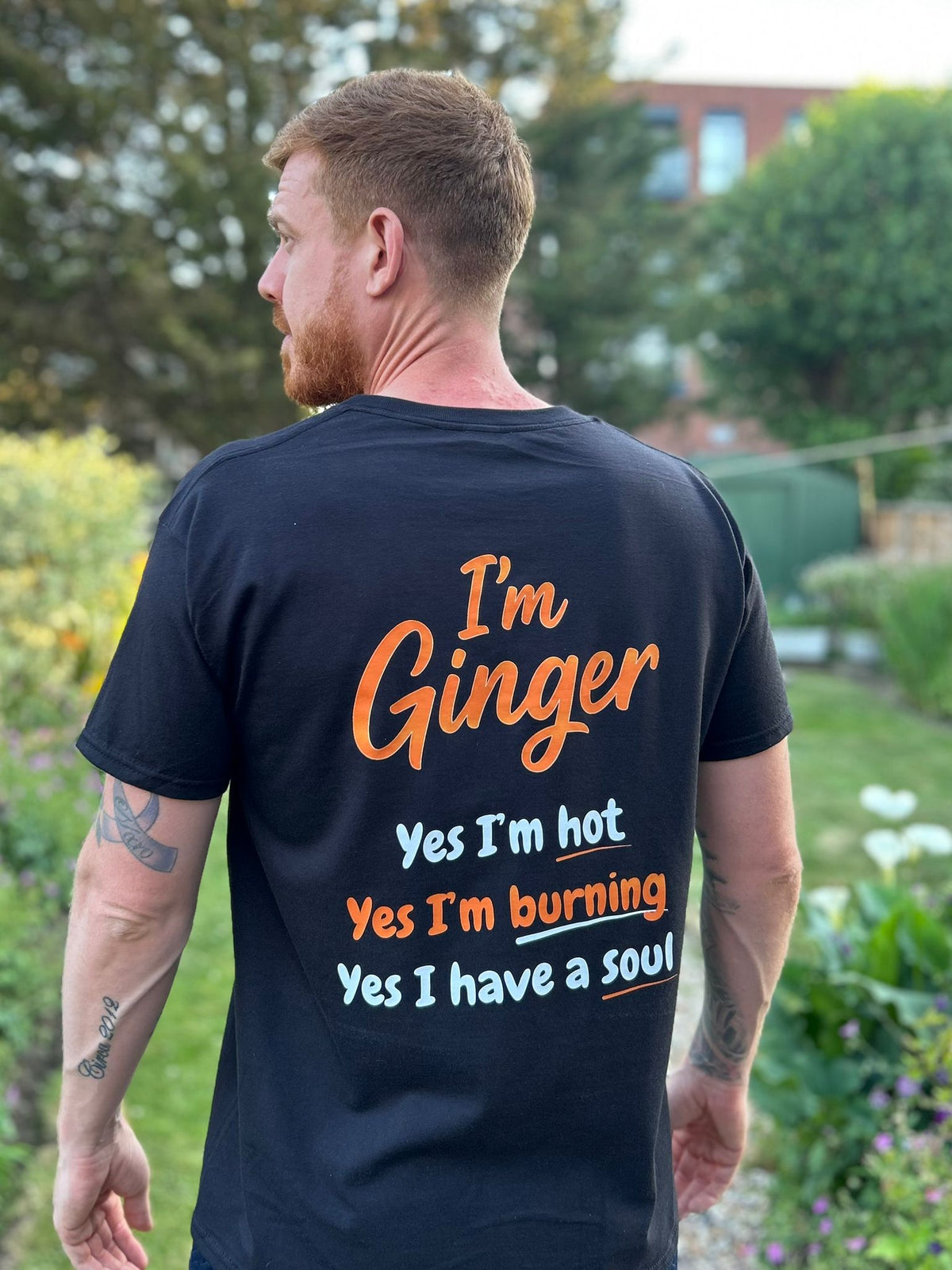 Man wearing a black t-shirt with text on the back in an outdoor setting