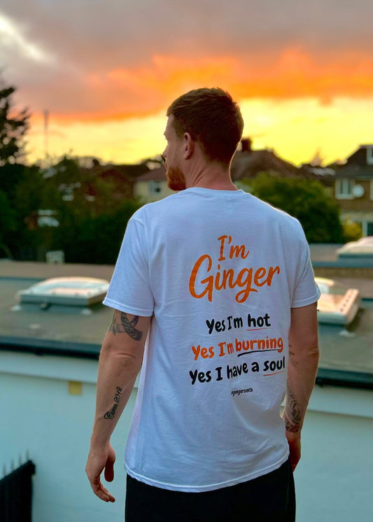Person wearing a white t-shirt with text standing on a rooftop at sunset.